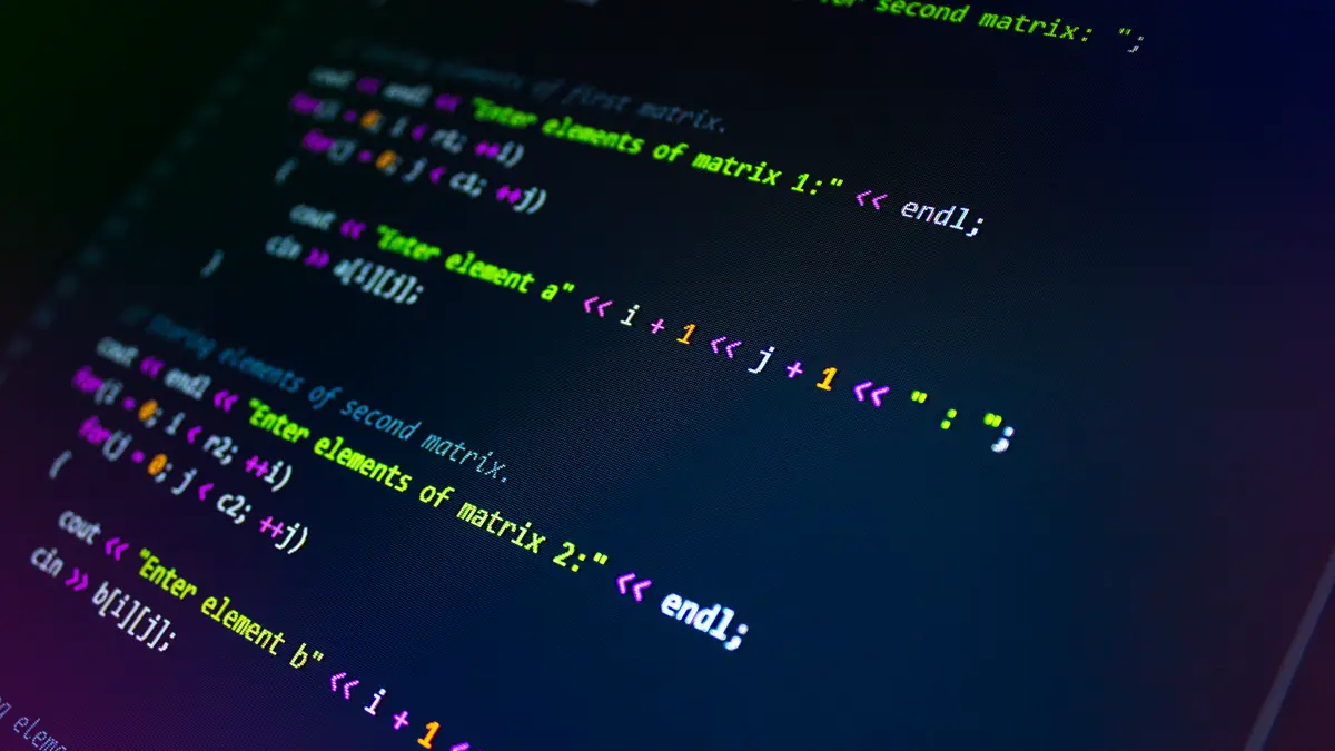 Programming code on a dark monitor viewed at an angle.