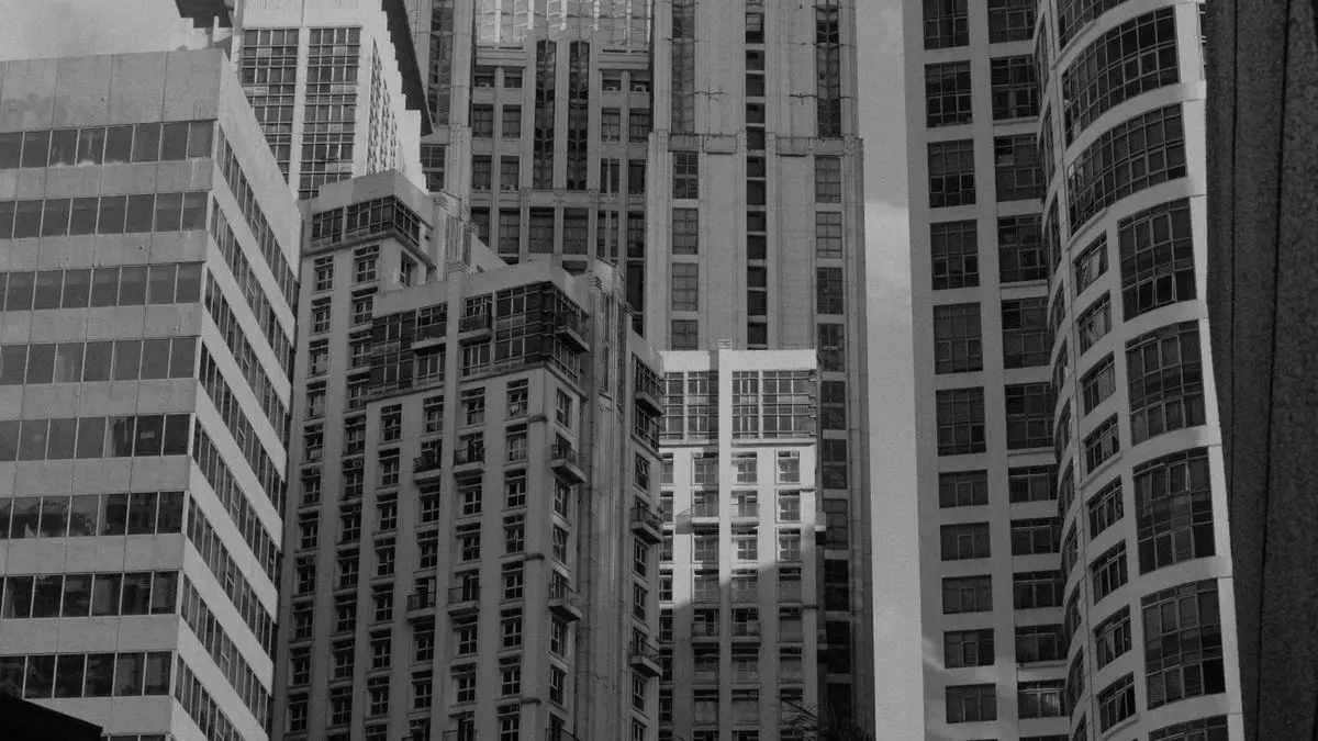 Black-and-white view looking up between skyscrapers.