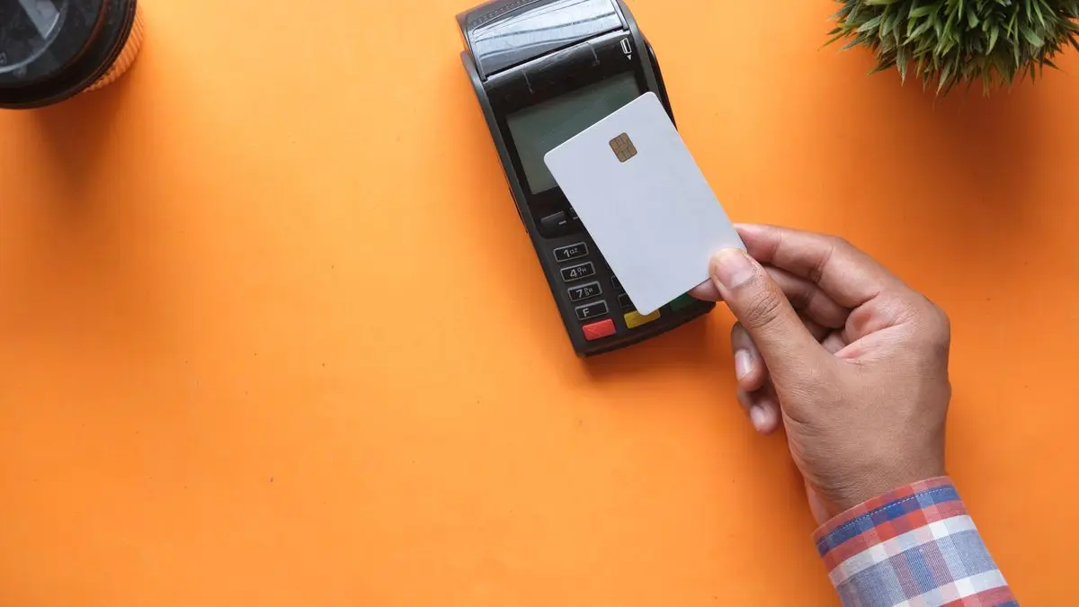 Payment card and terminal on an orange surface.