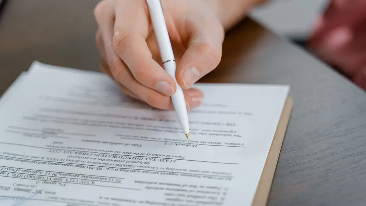 Close-up of a hand signing paperwork.