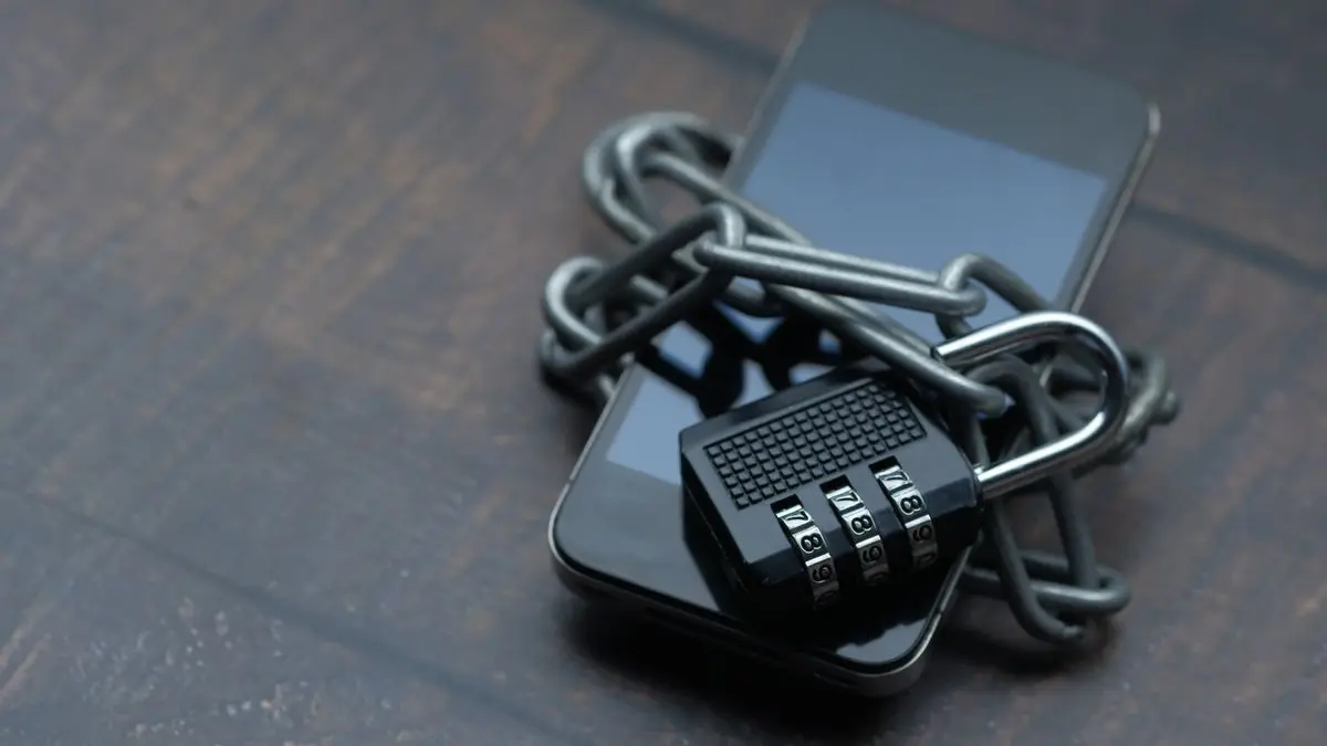 A smartphone wrapped in a chain and padlock.