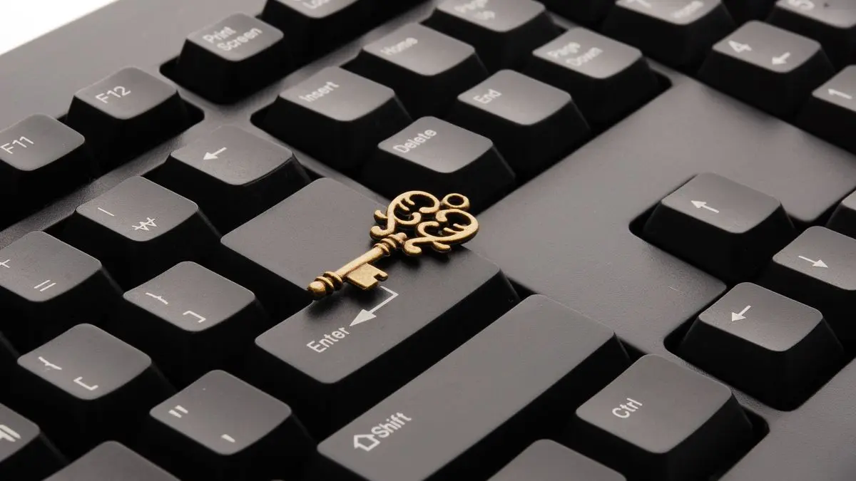 A decorative metal key resting on a computer keyboard.