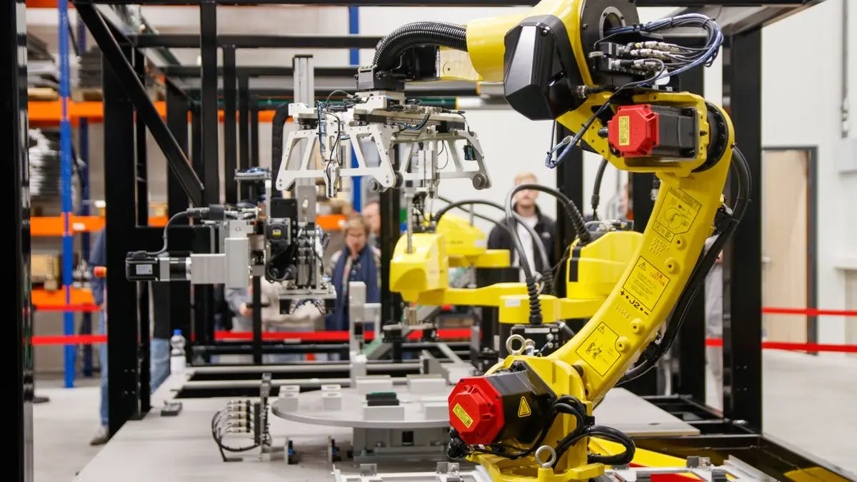 Yellow industrial robotic arm in a manufacturing area.