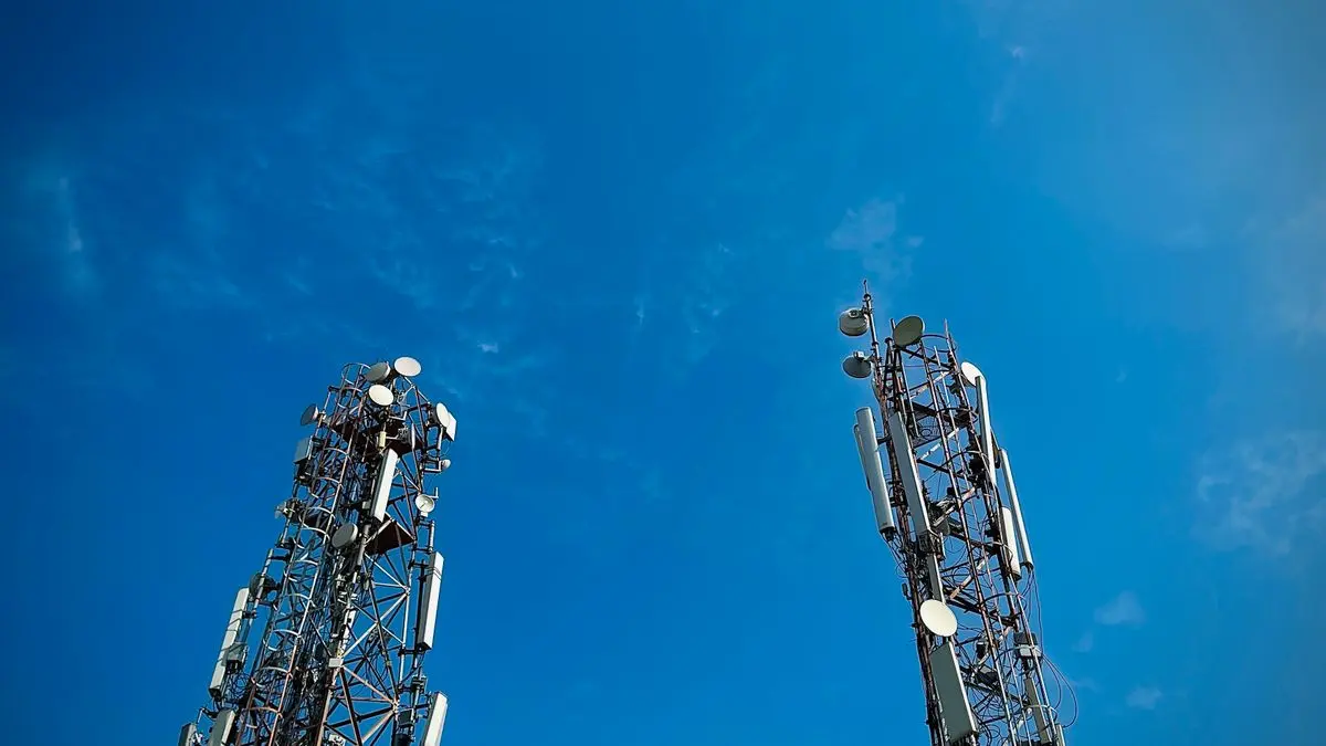 Two telecommunications towers against a blue sky.