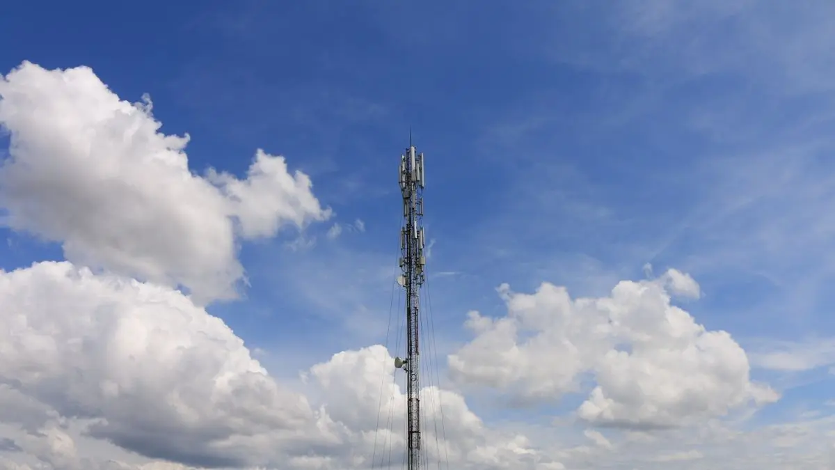 A slender communications tower beneath scattered clouds.