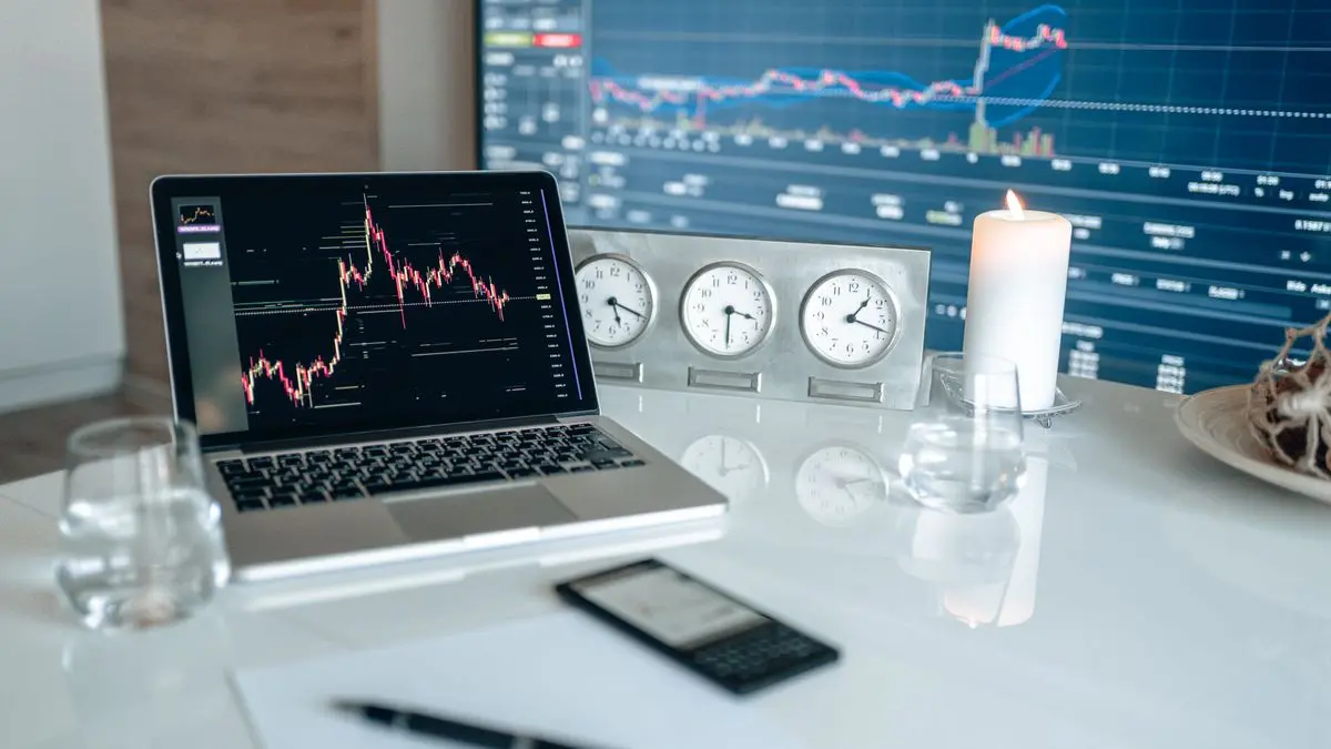 Trading screens, clocks and a laptop on a desk.
